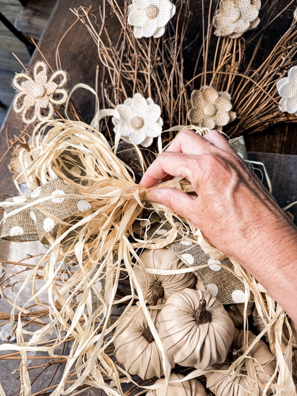 Add a burlap and raffia ribbon just above the cluster of pumpkins.  