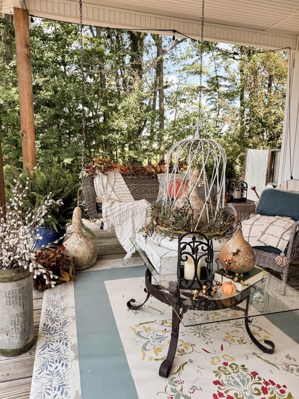 Fall Front Porch Decorating ideas for seating area with porch swing and vintage wicker rockers and iron coffee table.  