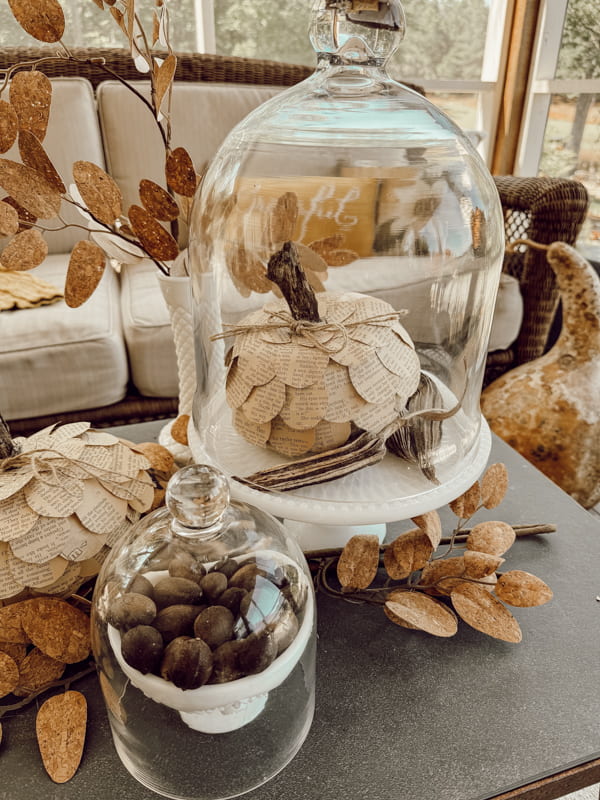 Milk glass cake stand with autumn vibe decorations in screened porch.