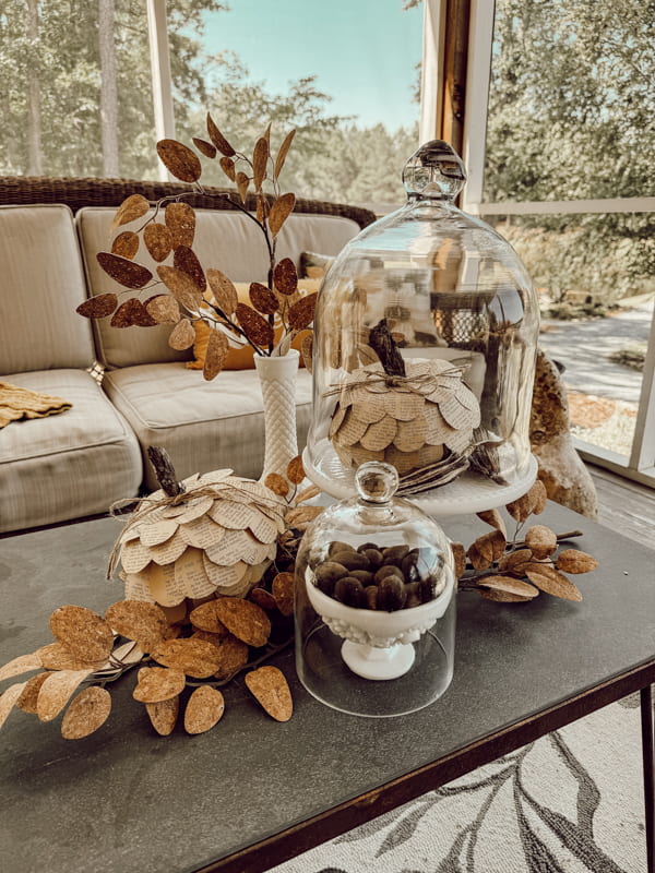 Fall coffee table milk glass centerpiece with glass cloches and DIY old book page Dollar Tree Pumpkins & milk glass cake stand.