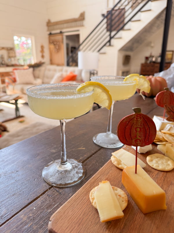 Two lemon Drop martinis with sugar rims and lemon slice garnish with a cheese tray and crackers