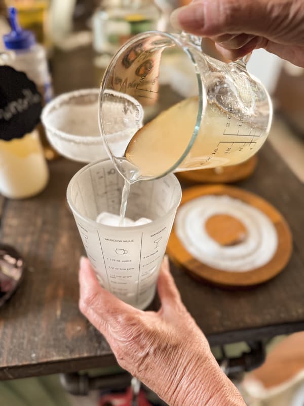 lemon drop martini ingredients being poured into a cocktail shaker with ice.  