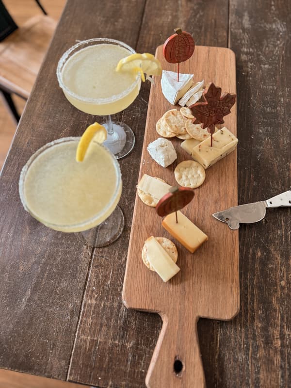 Two lemon Drop martinis with sugar rims and lemon slice garnish with a cheese tray and crackers