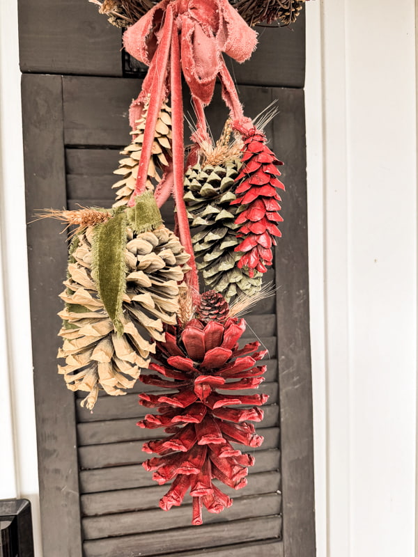 DIY pinecone swag on shutters. Painted pinecones and ribbon. 