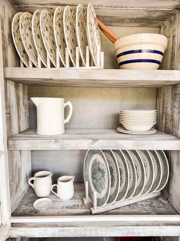 Vintage Dishes on plate stands in outdoor kitchen cabinet with blue and white vintage dinnerware sets  