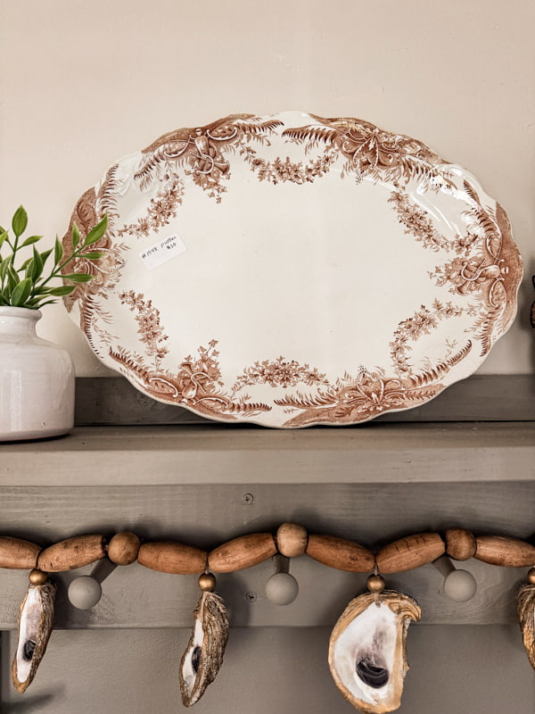 Thrifted brown transferware platter on shelf with DIY oyster garland.  