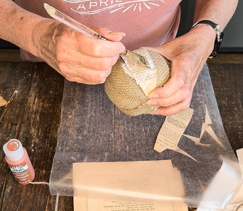 Add mod podge to the top of the old book page pumpkin for primitive fall craft