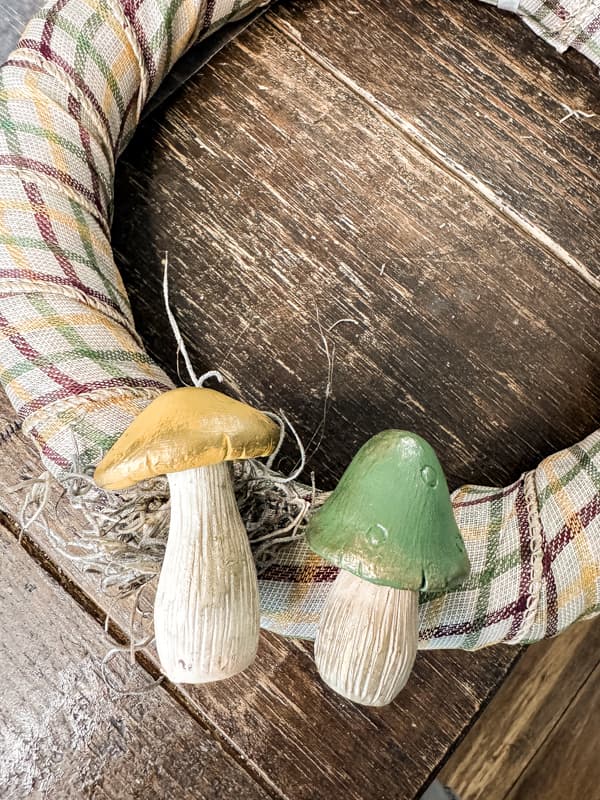 Use hot glue to attach spanish moss and Dollar Tree mushrooms to ribbon covered wreath