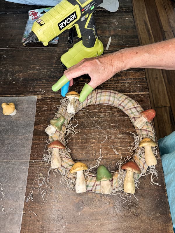 Use hot glue to attach spanish moss and Dollar Tree mushrooms to ribbon covered wreath