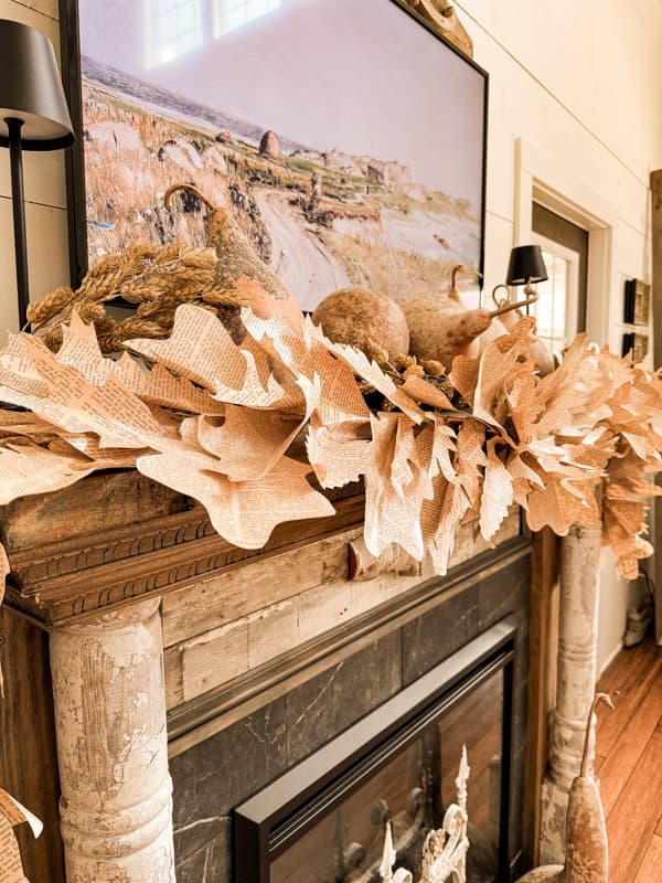 Rustic DIY Fall Leaf Garland made with upcycled old book pages on fall mantel with dried gourds. 