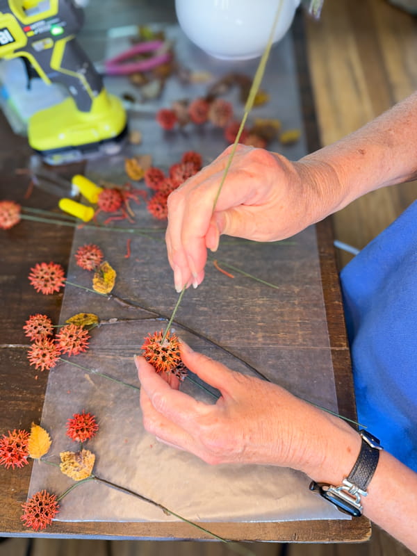 Place a floral wire into the sweet gum ball to make fall floral arrangement stem