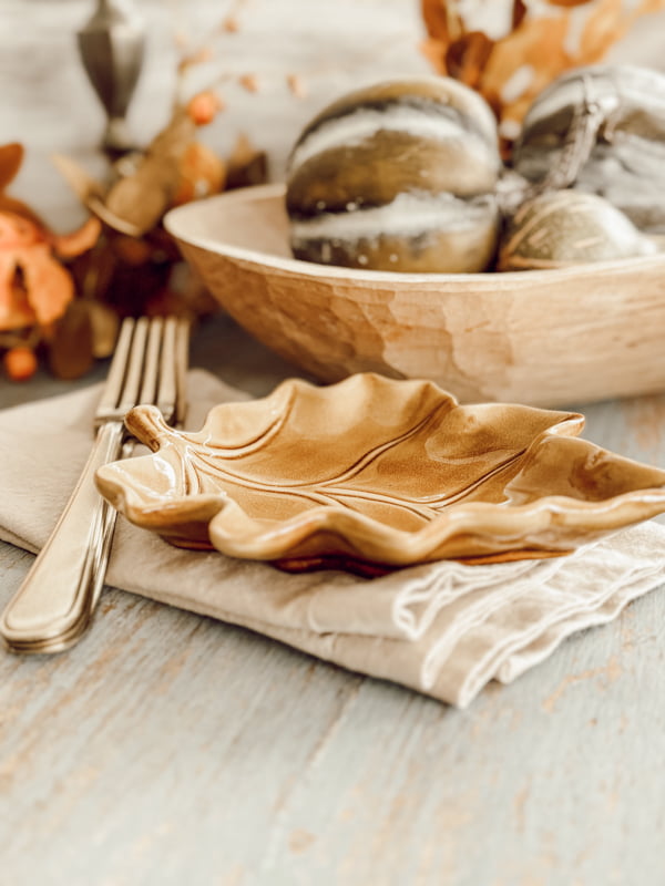 Golden fall leaf dish with napkins and gold silverware on Fall porch table.  