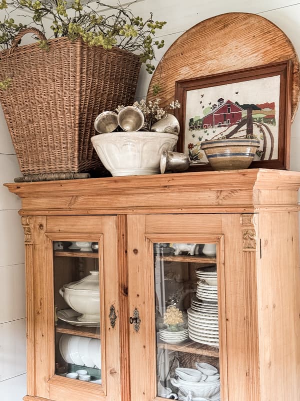 hutch with basket and vintage bowl storing out of season tableware