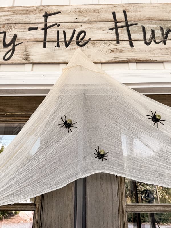 Cheese cloth table runner with Dollar Tree plastic spiders draped over the doorway for Halloween Decorations.