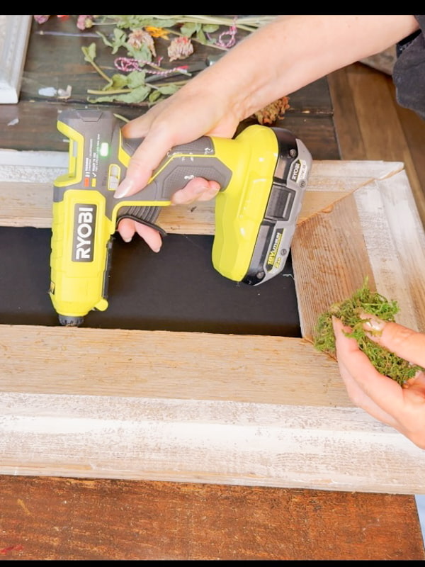 Adding moss to a DIY reclaimed wood frame with black background.  