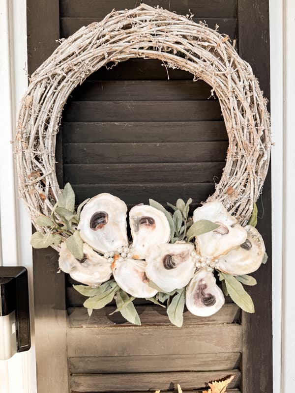 DIY Upcycled Christmas Oyster Shell Wreath on white grapevine wreath with green velvet ribbon.