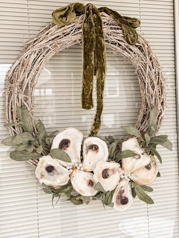 DIY Upcycled Oyster Shell Wreath on white grapevine wreath with green velvet ribbon.