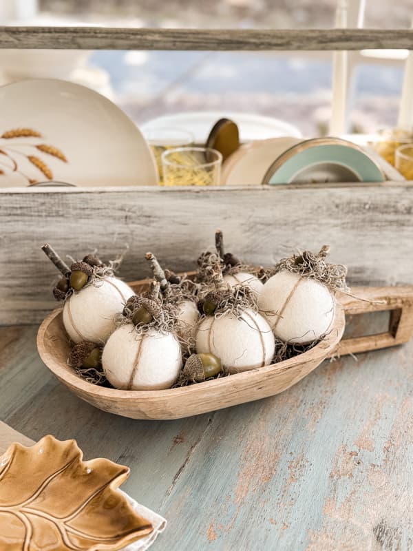 Small dough bowl filled with DIY pumpkin craft and acorns