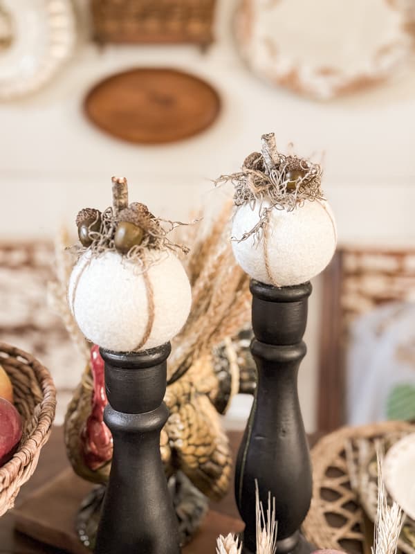 two wool dryer ball pumpkins on black candlestick holders.  