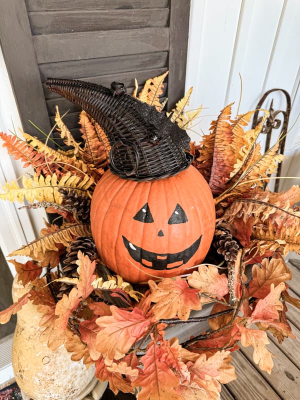 Add Jack O'Llantern with witches hat to the planters filled with fall leaves and ferns.  