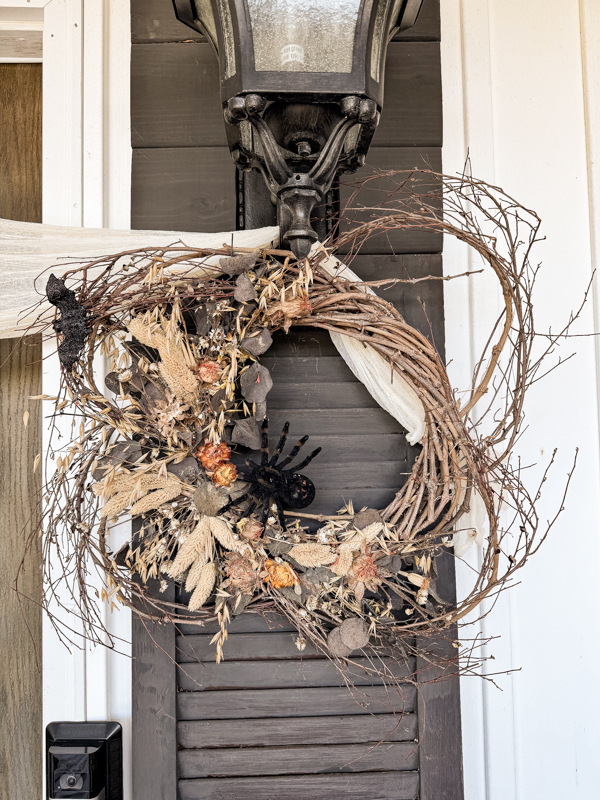 Add spiders and bats to fall wreath for a spooky outdoor halloween home decor idea