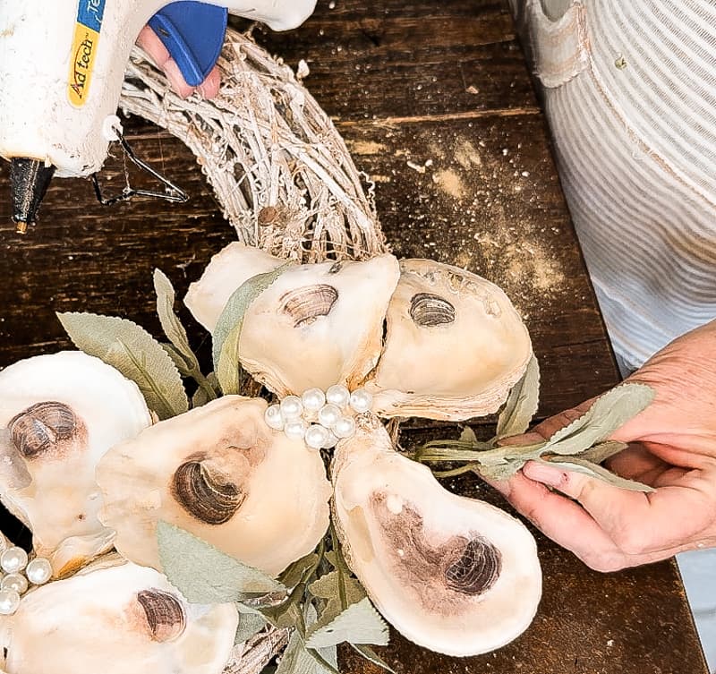 add faux greenery with hot glue around edges of oyster shells.