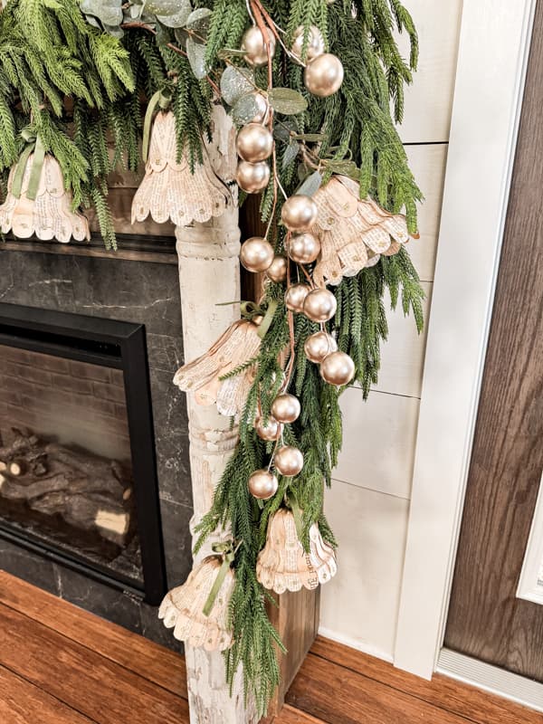 DIY Christmas Bells with old book pages on mantel greenery garland.