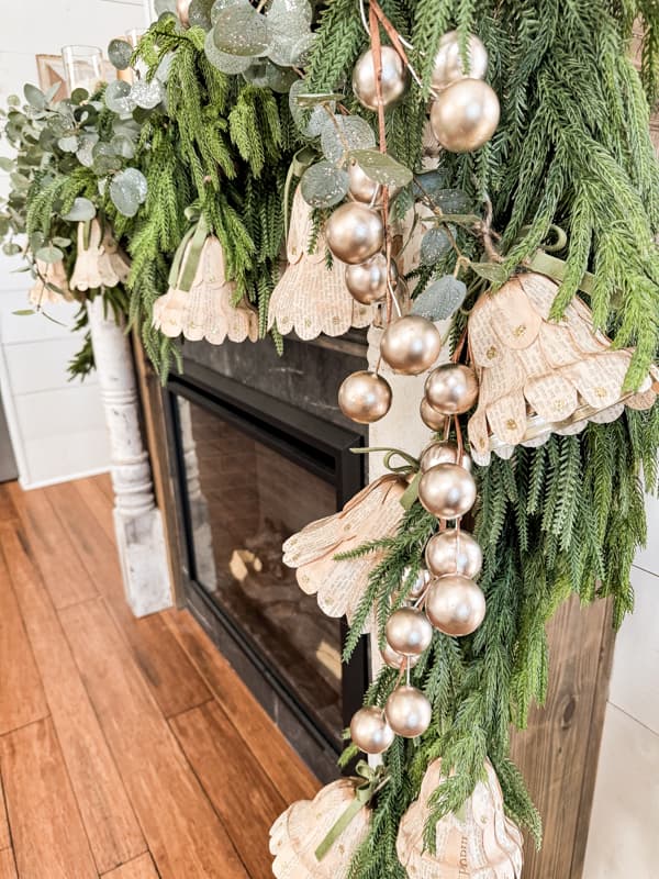 DIY Christmas Bells with old book pages on mantel greenery garland.