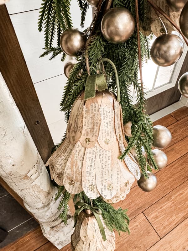 DIY Christmas Bells with old book pages on mantel greenery garland.