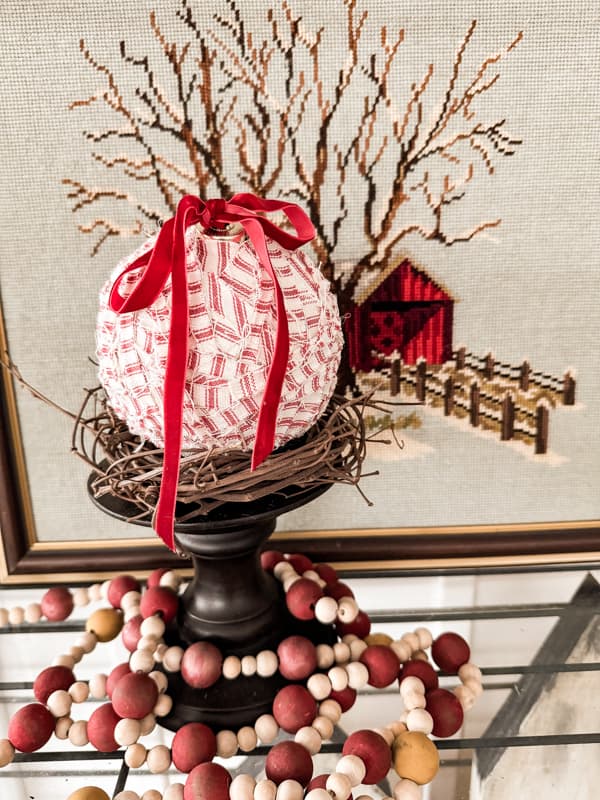 Red and White ticking strip fabric covered Dollar Tree Christmas ornament on a candle holder