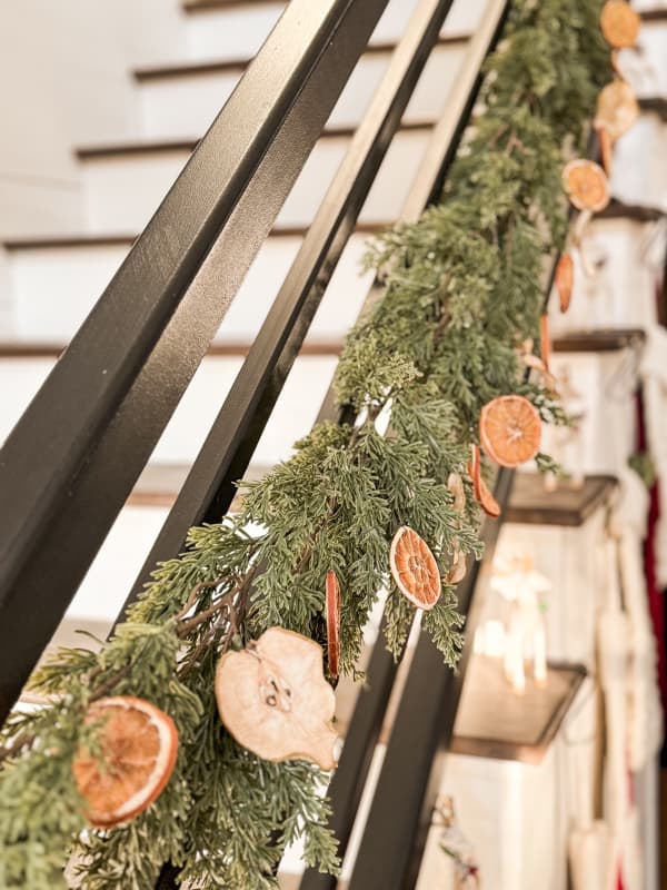 Dried Fruit Garland with oranges and pears on greenery garland on staircase banister.