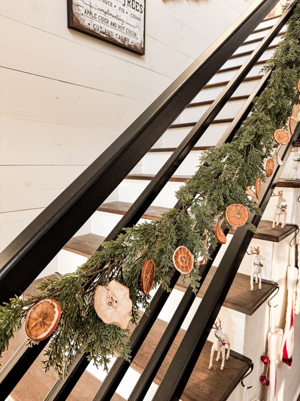 Dried Fruit Garland with oranges and pears on greenery garland on staircase banister.