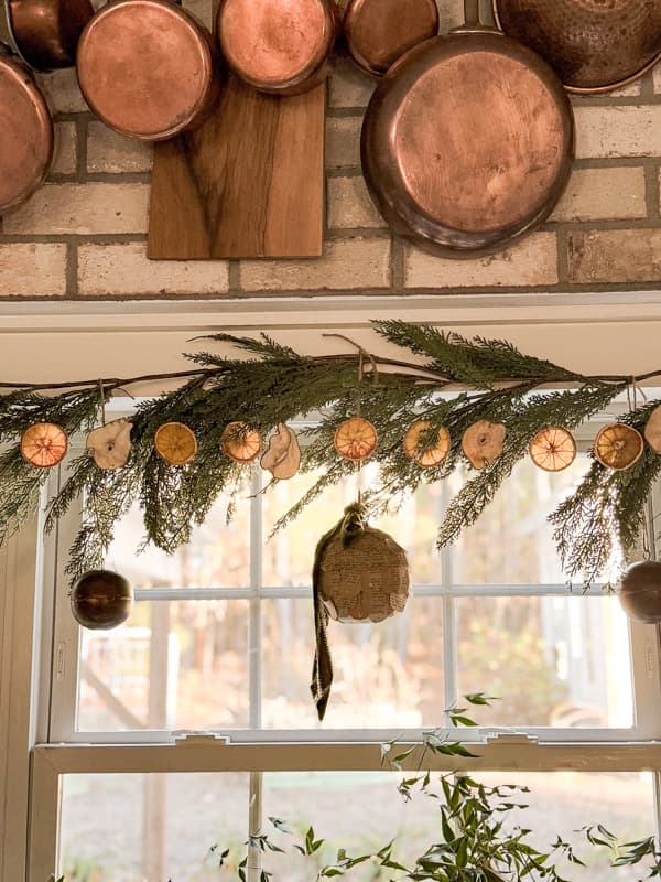 Dried Fruit Garland with oranges and pears on greenery garland in kitchen window.