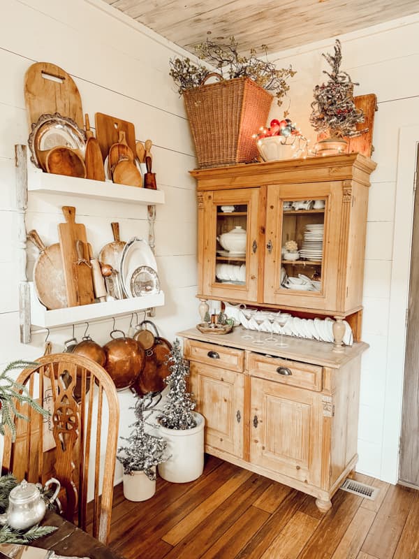 Farmhouse Kitchen hutch filled with white ironstone and DIY wall plate rack with vintage cutting boards and copper