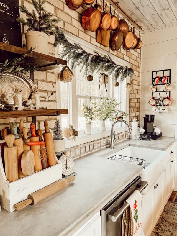 Farmhouse Christmas Kitchen decorated with copper and silver.  DIY window garland with old book page ornaments.