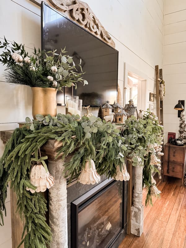 Farmhouse Shabby Chic Mantel with norfolk pine garland, DIY Paper Christmas Bells, DIY Candle Holders and old book page rustic village.