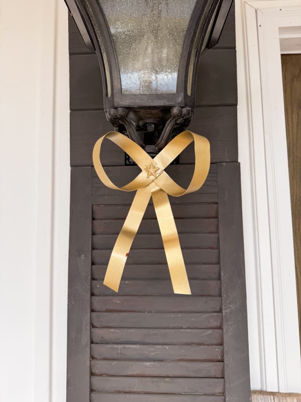 Gold metal Chirstmas bow on porch light fixture