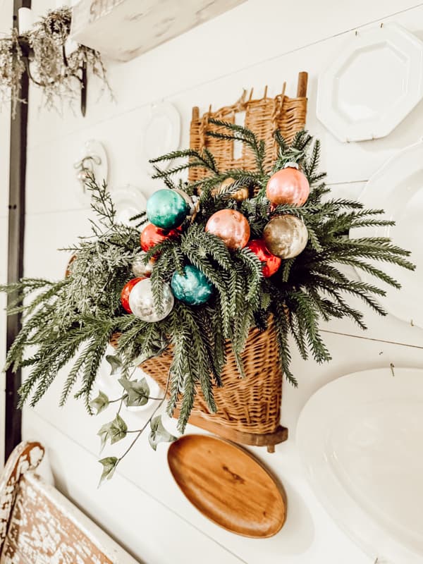 Vintage European Gathering Basket filled with greenery and vintage glass Christmas Ornaments.  