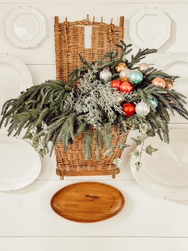 Vintage European Gathering Basket filled with greenery and vintage glass Christmas Ornaments.  