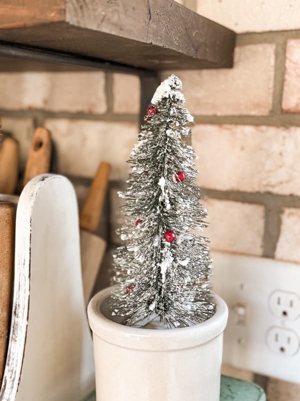 Snowy tree with red berries in vintage crock.