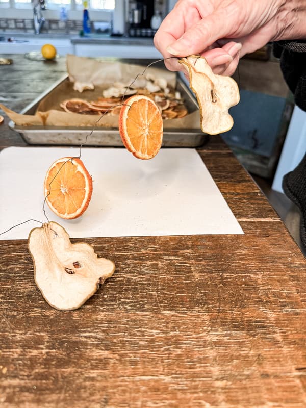 Add dried pears and oranges to wire for garland 