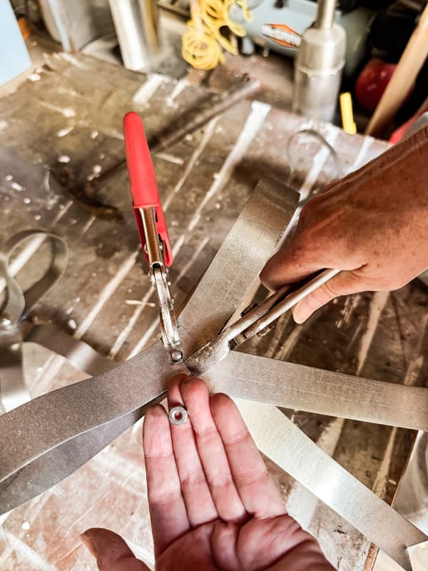 Add nut and bolt to create Christmas tree bow with metal strapping.