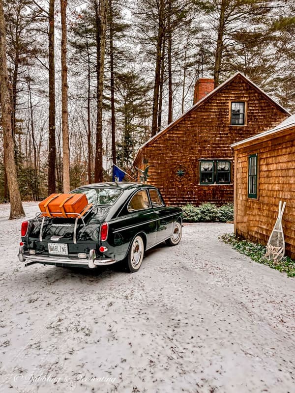 Vintage car with suitcase on trunk at Maine Cottage with cedar shakes.  