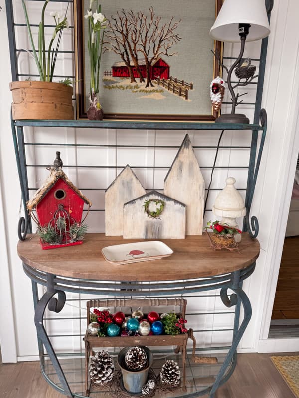 Bakers rack on screened porch filled with DIY and thrift store finds.