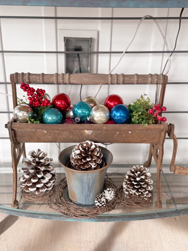 Vintage Paper Roller with old Christmas Ornaments and pinecones.