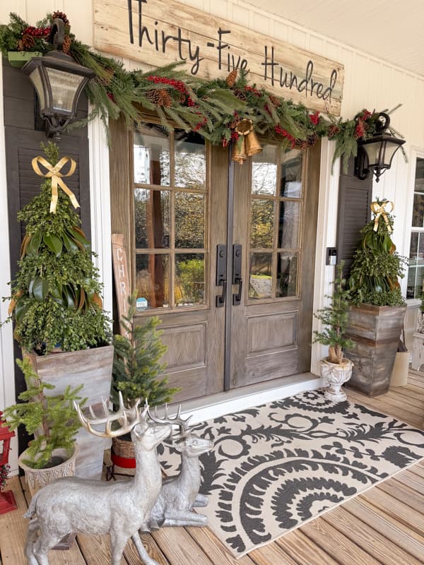 Outdoor Christmas Decorating Ideas for the front porch with greenery Christmas Trees and reindeer.