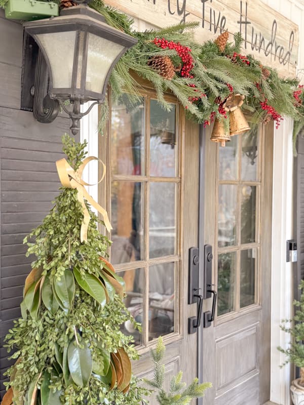 DIY Greenery Trees with gold bows anchor the front doors to the farmhouse.  