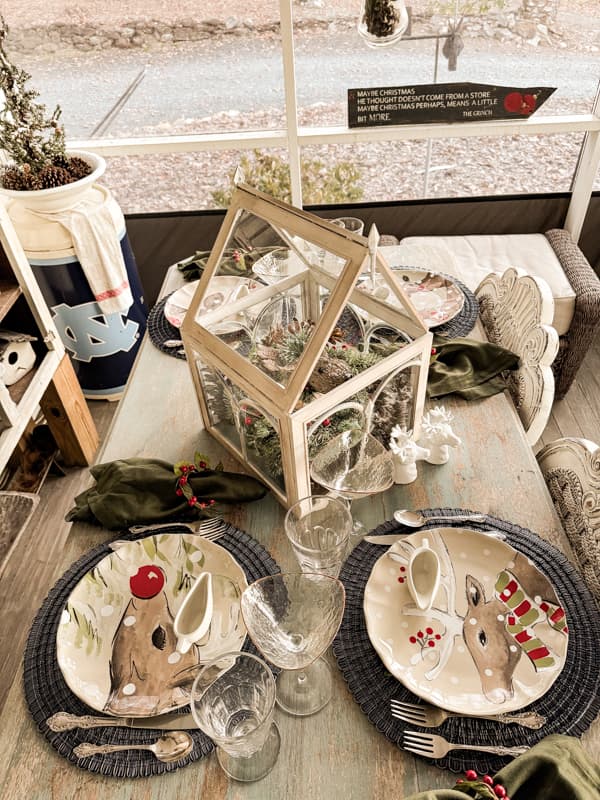 Reindeer dishes on outdoor porch dining table for outdoor Christmas Tablescape ideas.