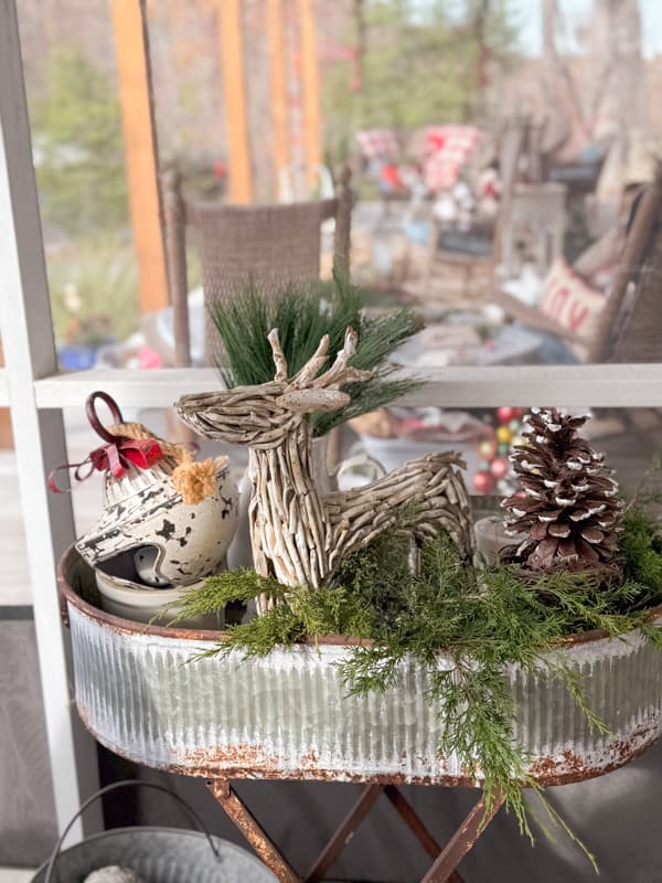 Planter filled with greenery, pinecones and a wooden reindeer.  