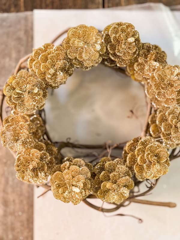 Gold glitter pinecones on a grapevine ring.